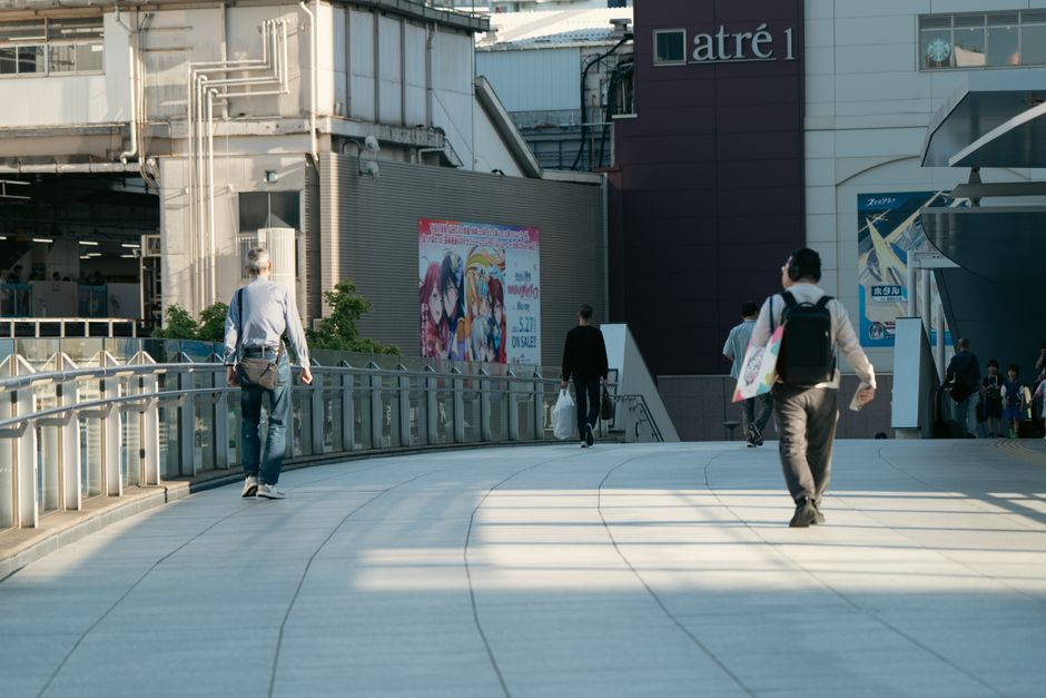 日本の東京にあるアトレビル近くの、陽光が差し込む小道を歩く人々。