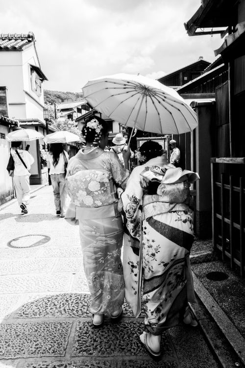 Free Black and white street scene capturing women in kimonos with umbrellas, Kyoto, Japan. Stock Photo