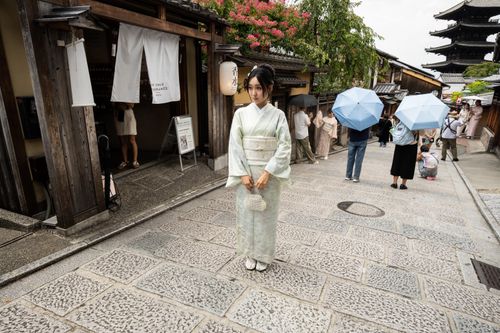 Free A woman in a kimono stands on a traditional Kyoto street with pagoda in the background. Stock Photo