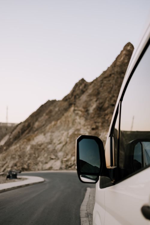 Free Captivating roadside view in Oman showcasing a van against rocky terrain at sunset. Stock Photo