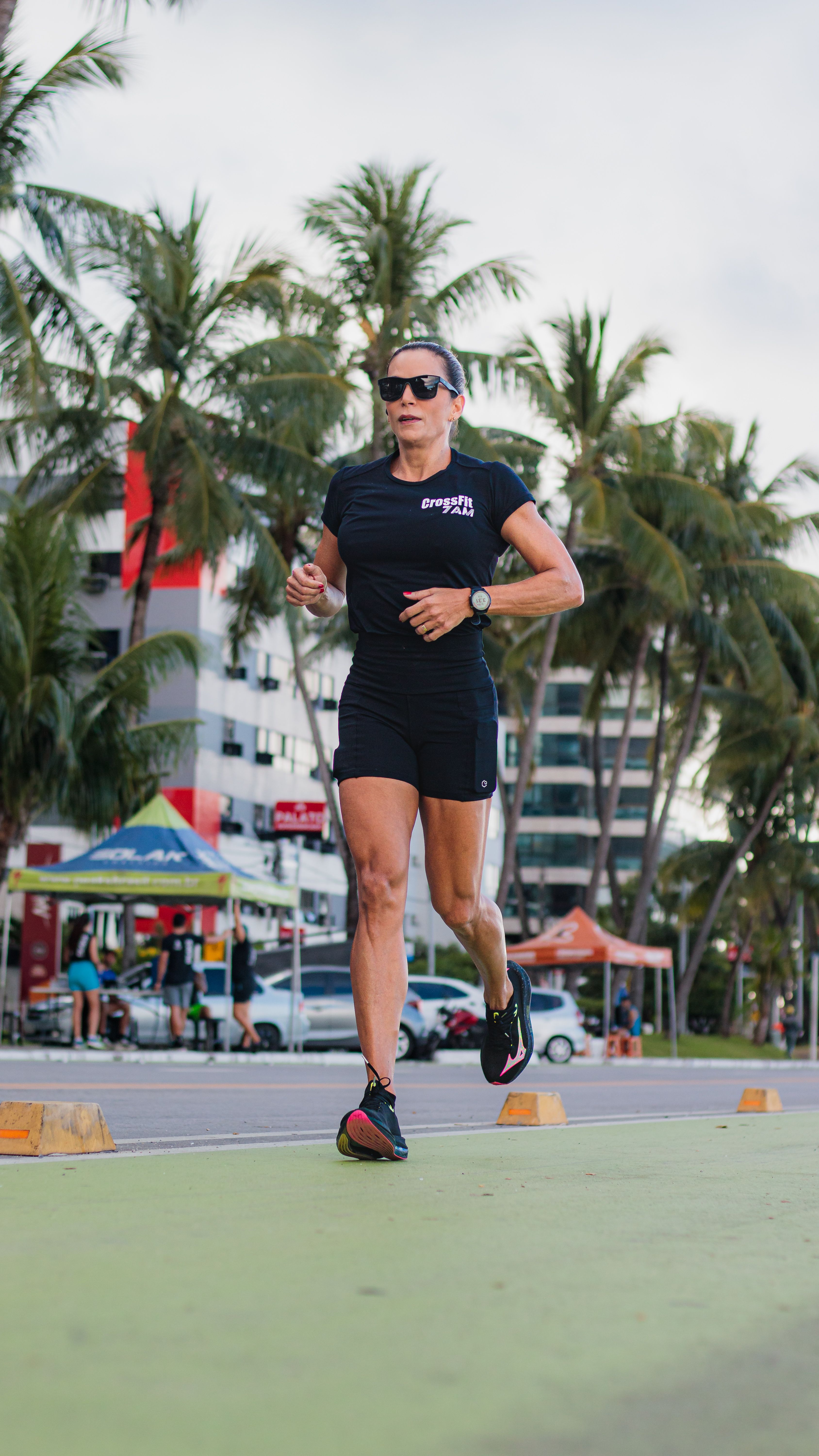 Female runner exercising outdoors in a vibrant tropical urban setting with palm trees.