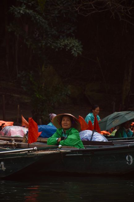 Locals in traditional boats at a serene river setting in Hanoi, Vietnam. Calm and cultural atmosphere.