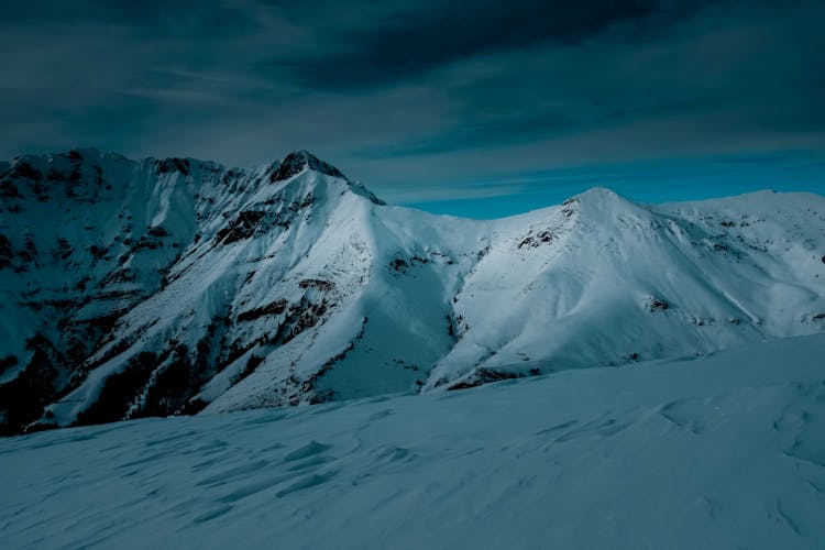 Snow Covered Mountain Under Cloudy Sky