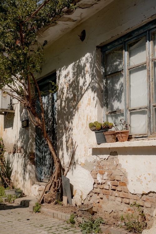 Free A vintage-style old house with peeling paint and potted plants, capturing rustic charm. Stock Photo