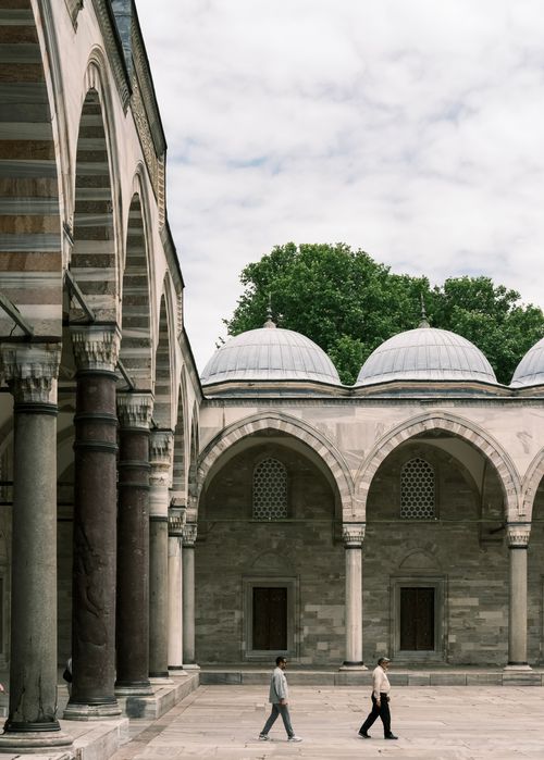Free Two men walk in the courtyard of the Suleymaniye Mosque in Istanbul, showcasing beautiful Ottoman architecture. Stock Photo