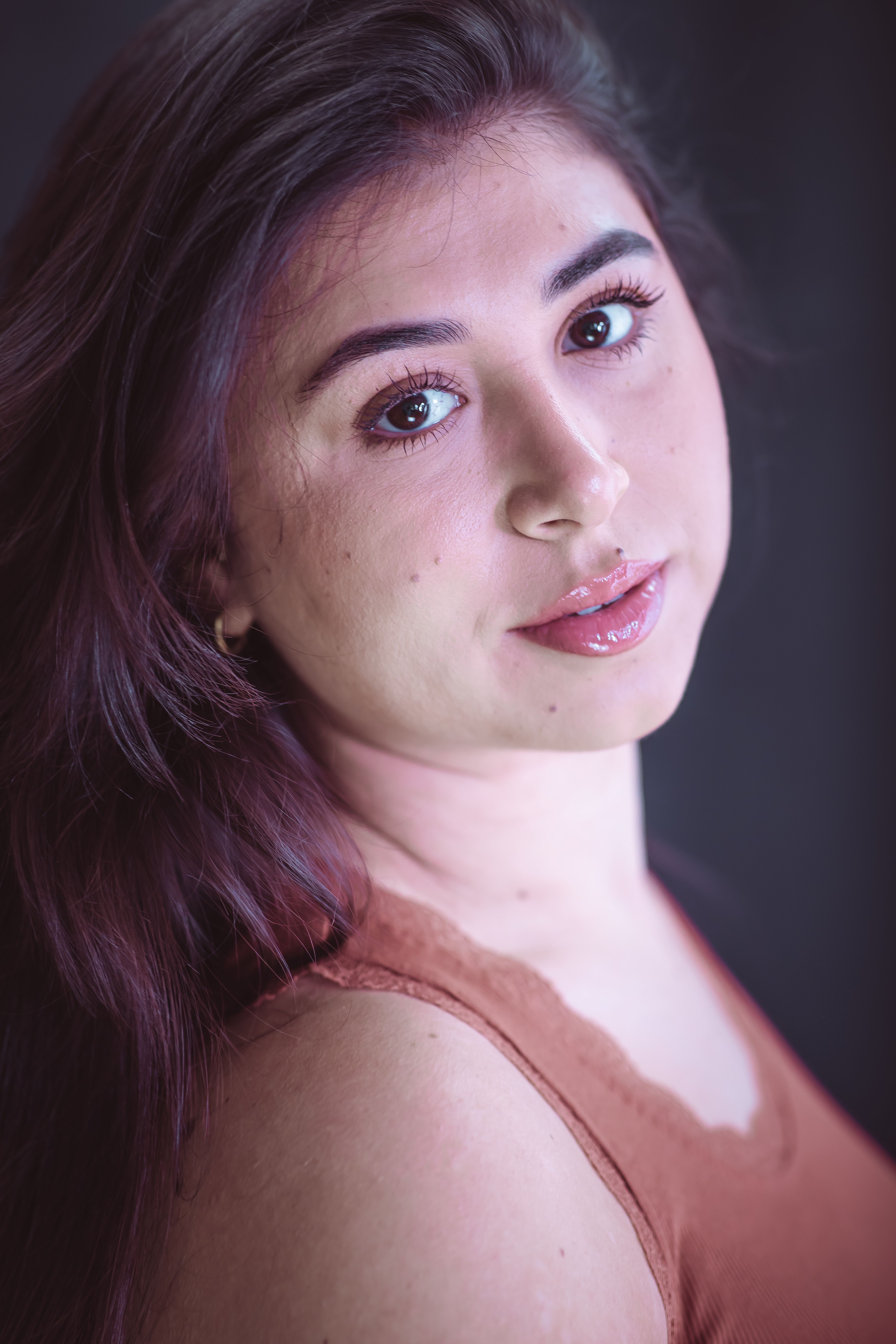 Close-up portrait of a young woman with long hair, gazing softly at the camera.