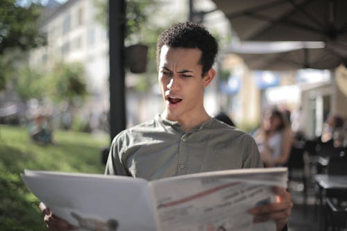 Free Shallow Focus Photo of Man Reading Newspaper Stock Photo