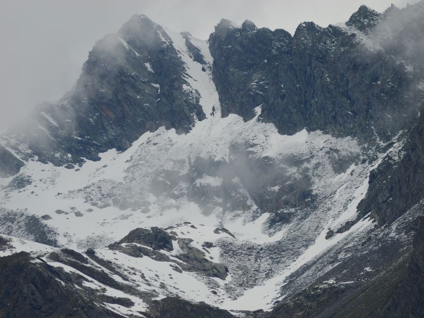 Majestic snow-covered mountain peaks with misty clouds on a winter day.