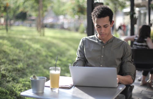 集中在街頭咖啡館中使用筆記本電腦的黑人男性自由職業者
