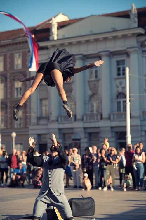 Free Dynamic street performers showcase acrobatic skills in a bustling city square. Stock Photo