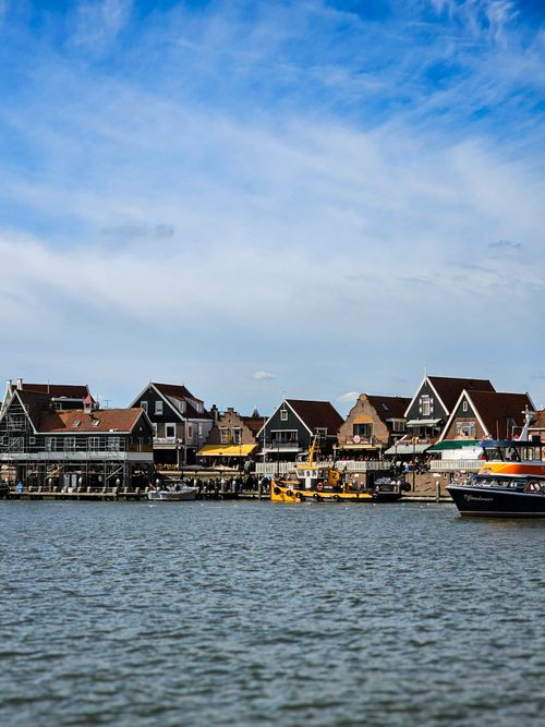 Free Scenic view of a picturesque village by the water with boats docked under a bright blue sky. Stock Photo
