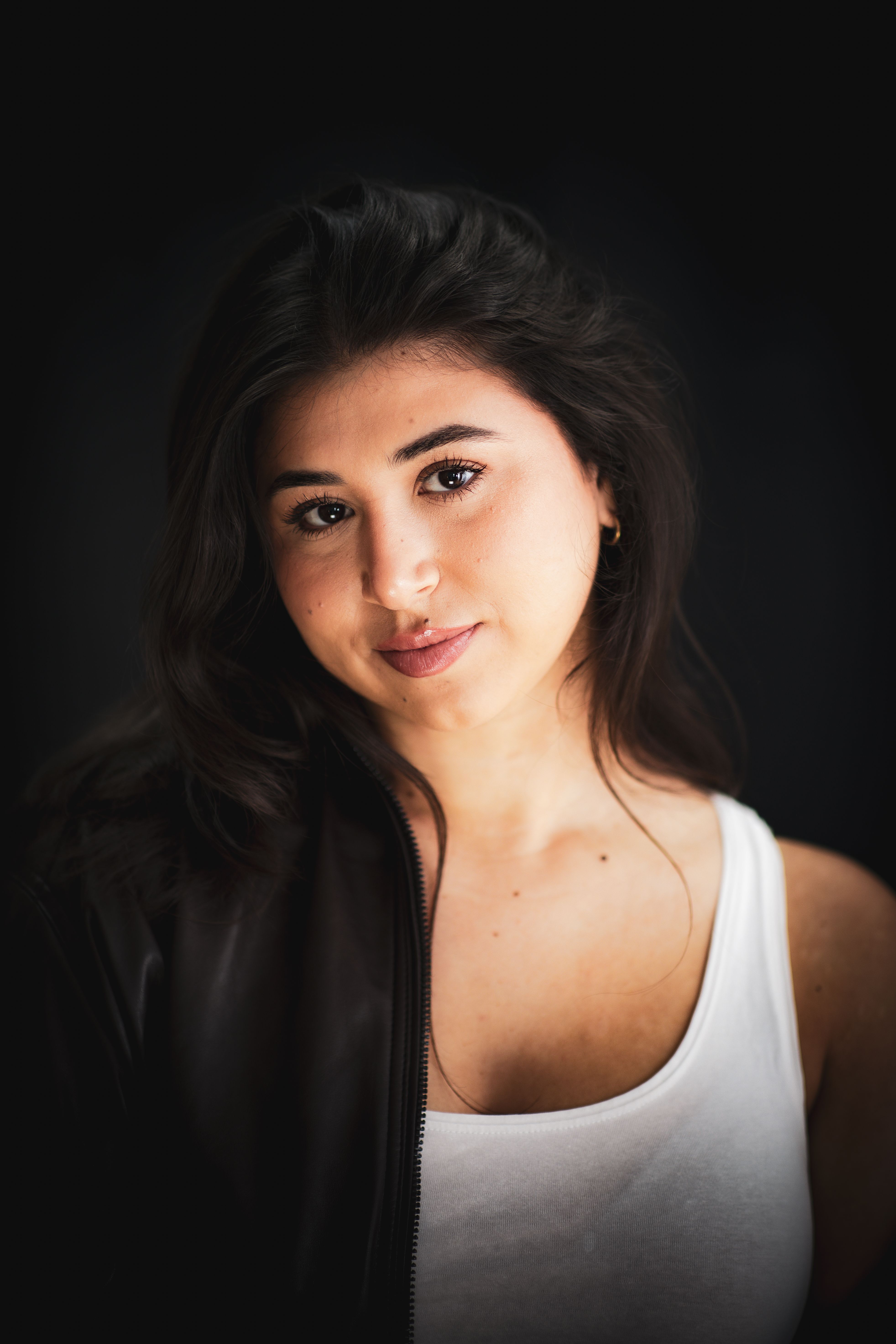 Close-up portrait of a young woman with soft lighting and a dark background.