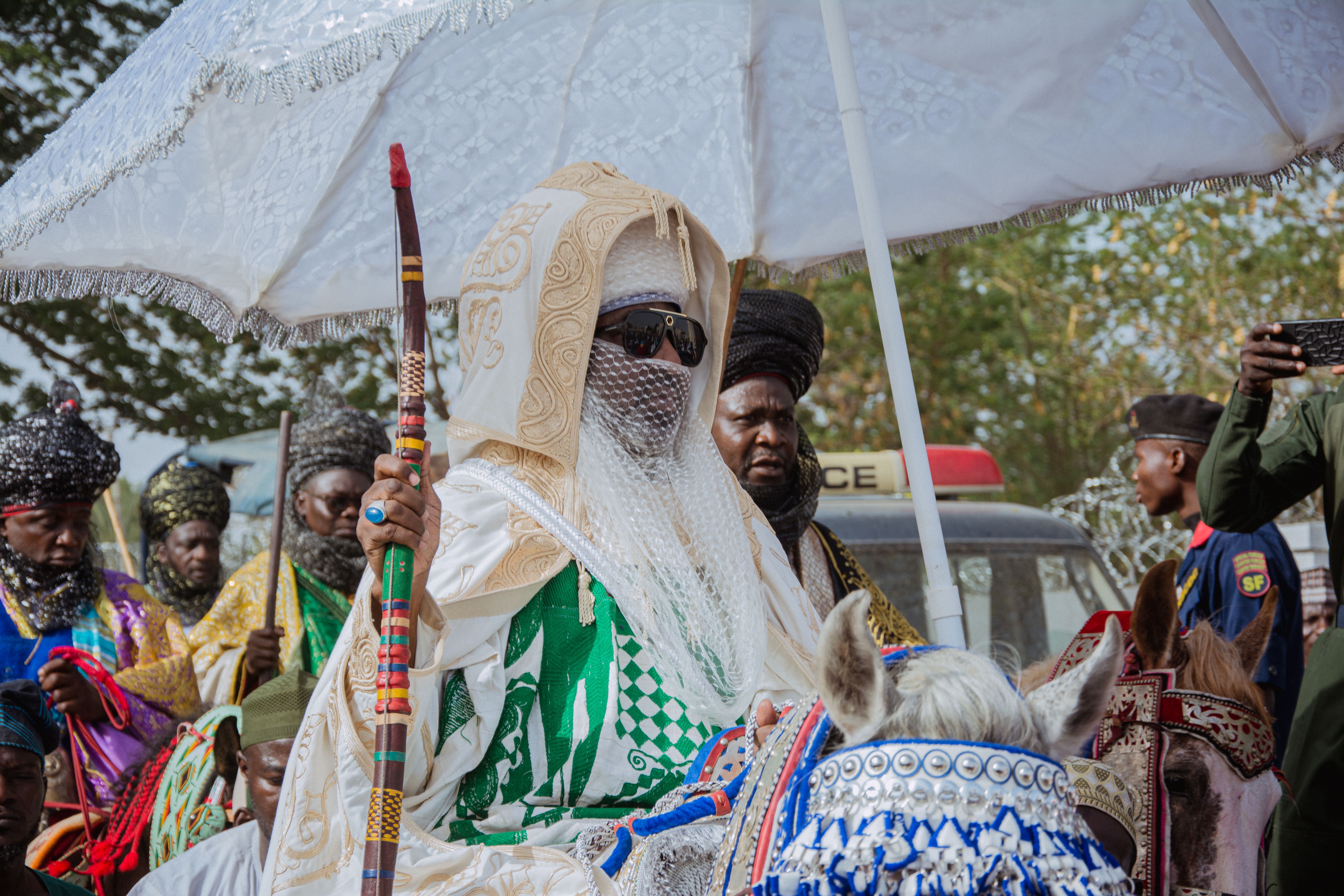 A Nigerian royal procession with elaborately dressed people on horseback, showcasing cultural and traditional attire.