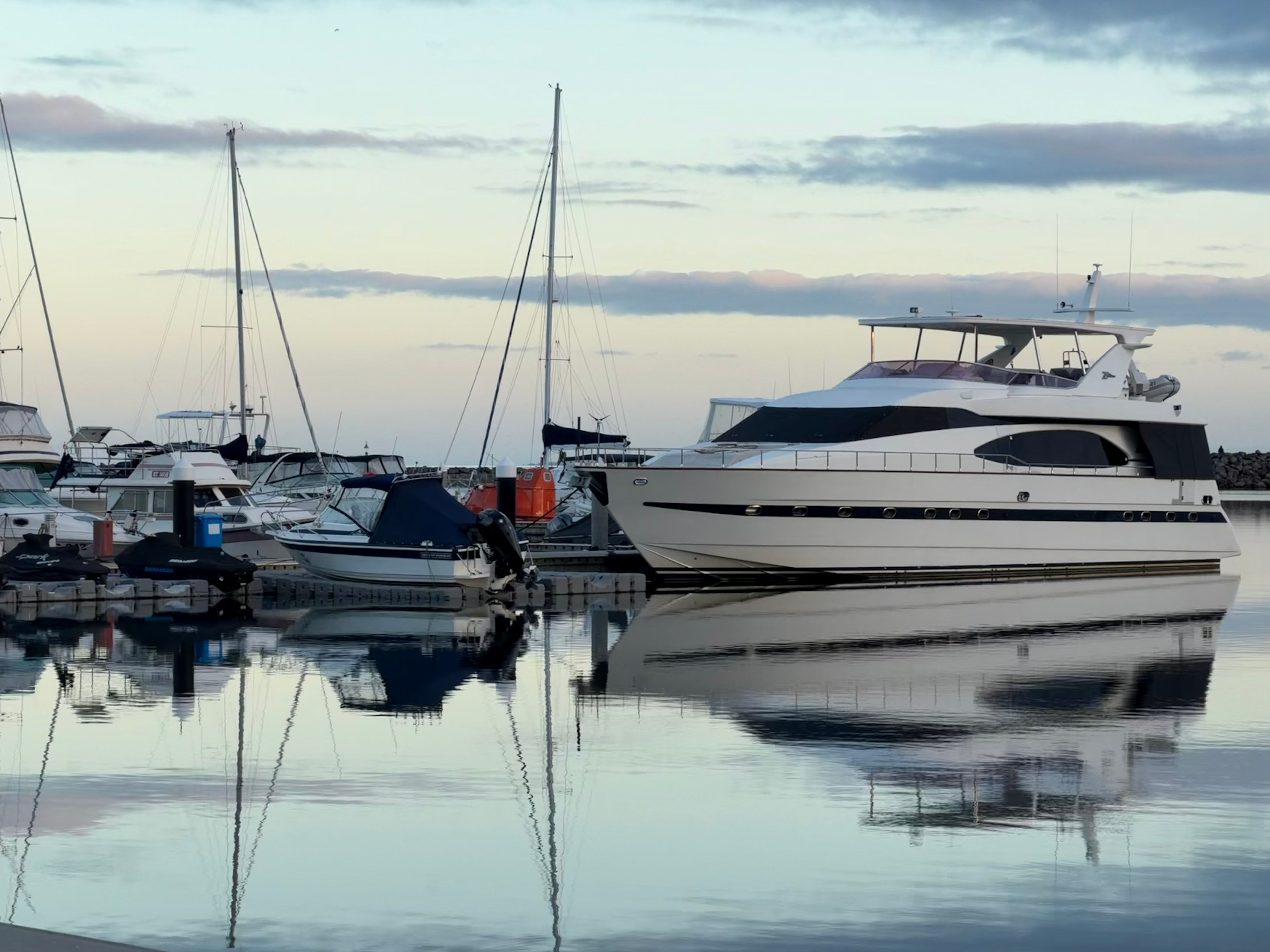 Serene view of luxury yachts reflecting on still waters at twilight in Werribee South Harbour, Victoria, Australia.
