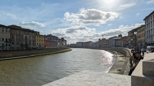 Free Picturesque view of the Arno River flanked by historic buildings in Pisa, Italy, under a sunny sky. Stock Photo