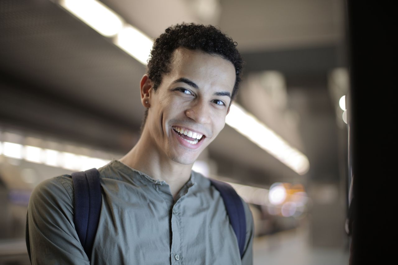 low angle of joyful charismatic african american male in gray shirt wi