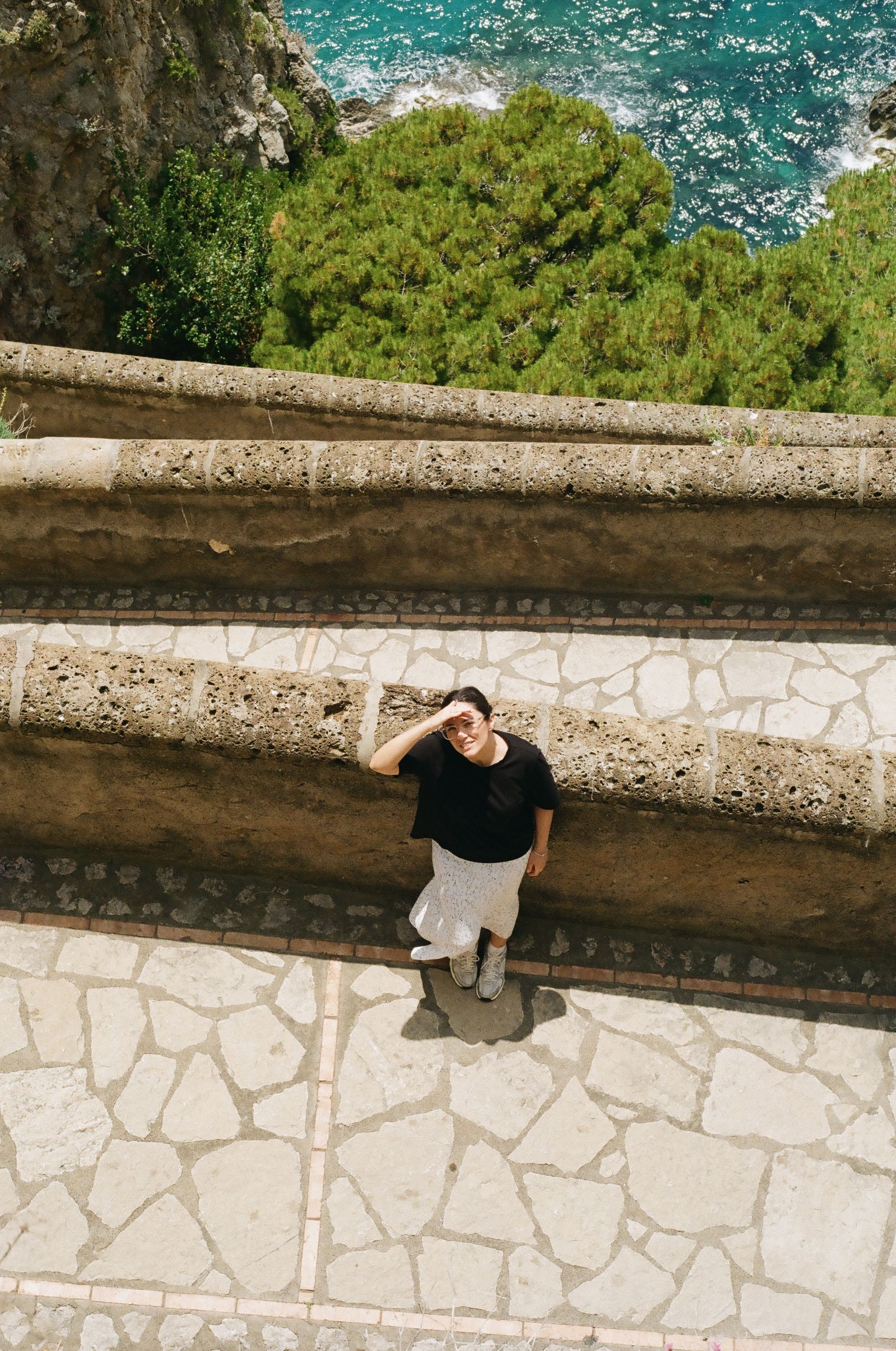 A person enjoys a scenic view from a stone terrace in Capri, Italy.