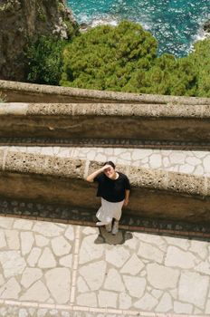 A person enjoys a scenic view from a stone terrace in Capri, Italy.