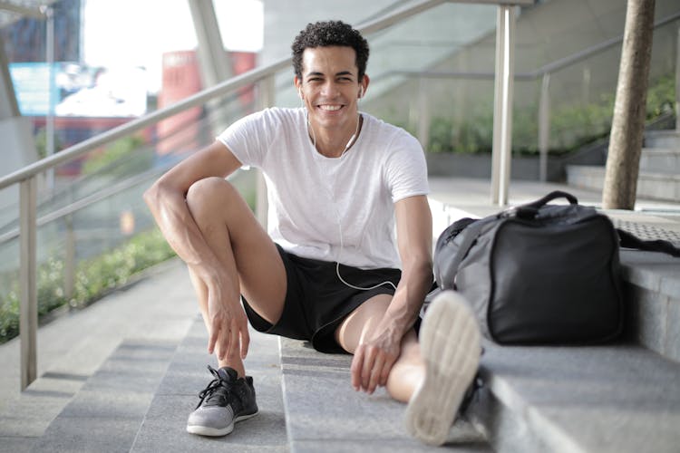 Happy Young African American Male Athlete Listening To Music And Resting After Training On Stairs On Street