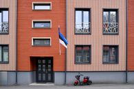 Contemporary apartment facade in Tallinn with the Estonian flag and an electric scooter parked outside.