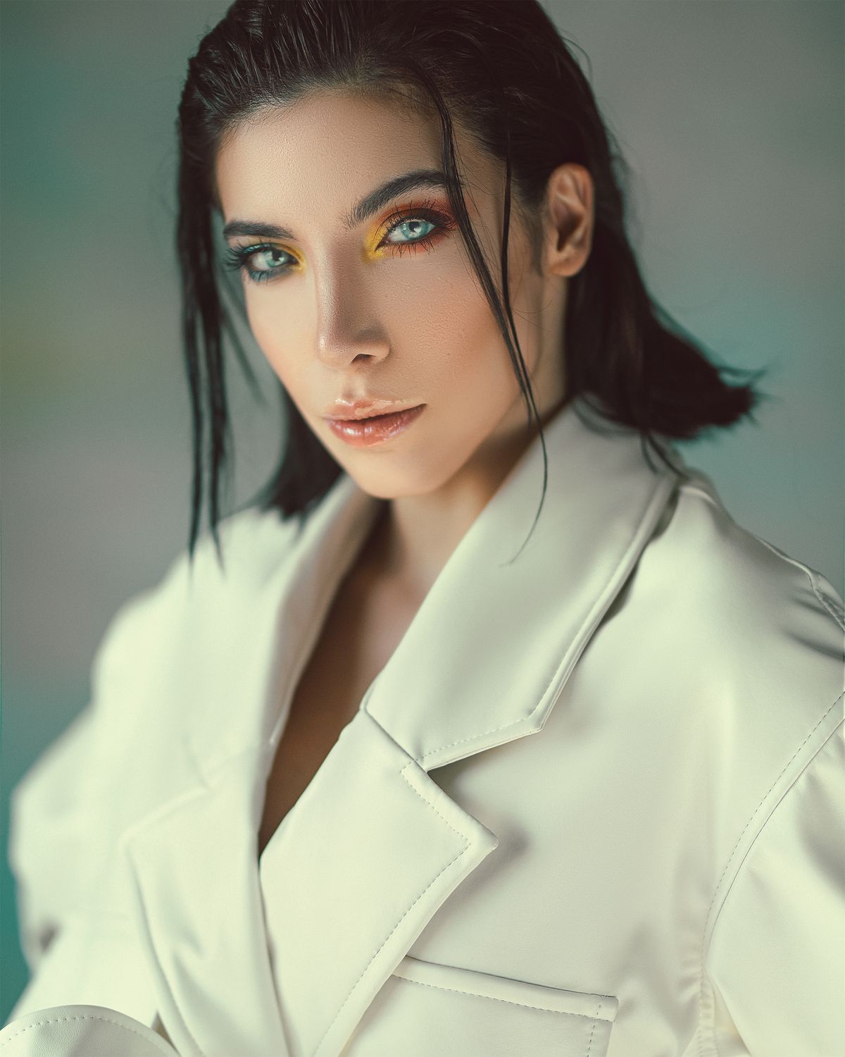 Stylish woman with vivid colored eye makeup against a white background