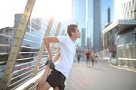 年轻人在城市桥上穿着运动服伸展，展现城市健身生活方式