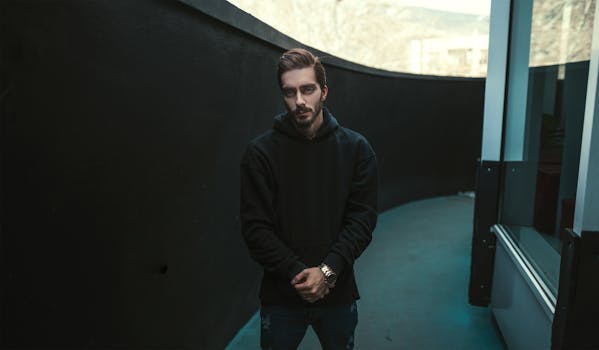 一个现代人身穿黑色连帽衫，在城市环境中摆出姿势