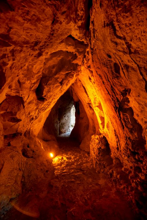 Free Explore a mystical cave illuminated by warm orange light, creating an enigmatic atmosphere within its rocky walls. Stock Photo