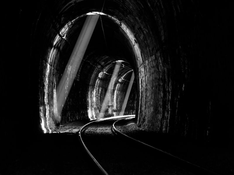 A railway tunnel piercing a dark mountainside
