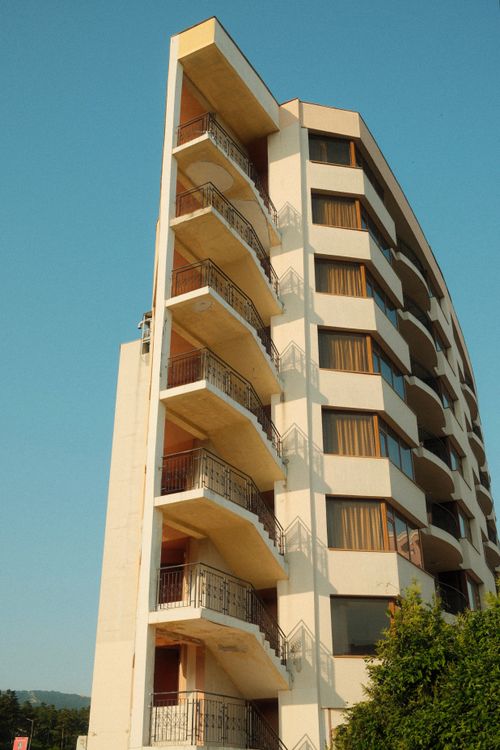 Free High-rise apartment building with multiple balconies under a clear blue sky. Stock Photo