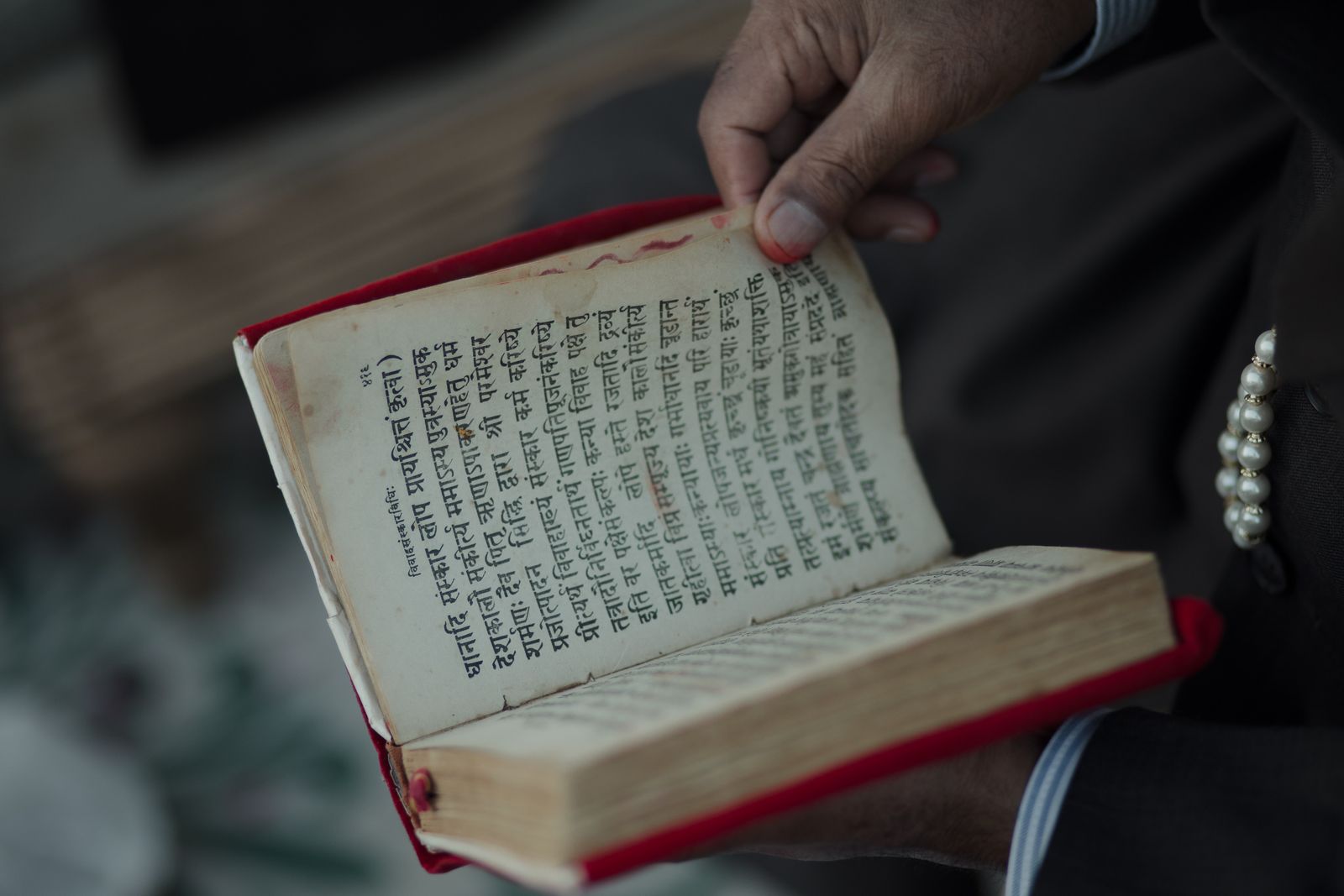 Hands holding an ancient Sanskrit text representing the Yoga Sutra tradition
