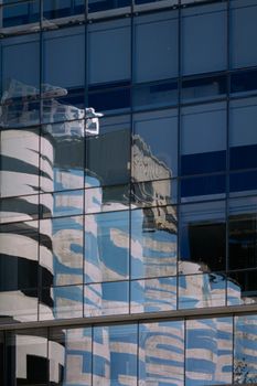 Glass facade in Buenos Aires reflecting urban architecture with blue sky and geometric patterns.