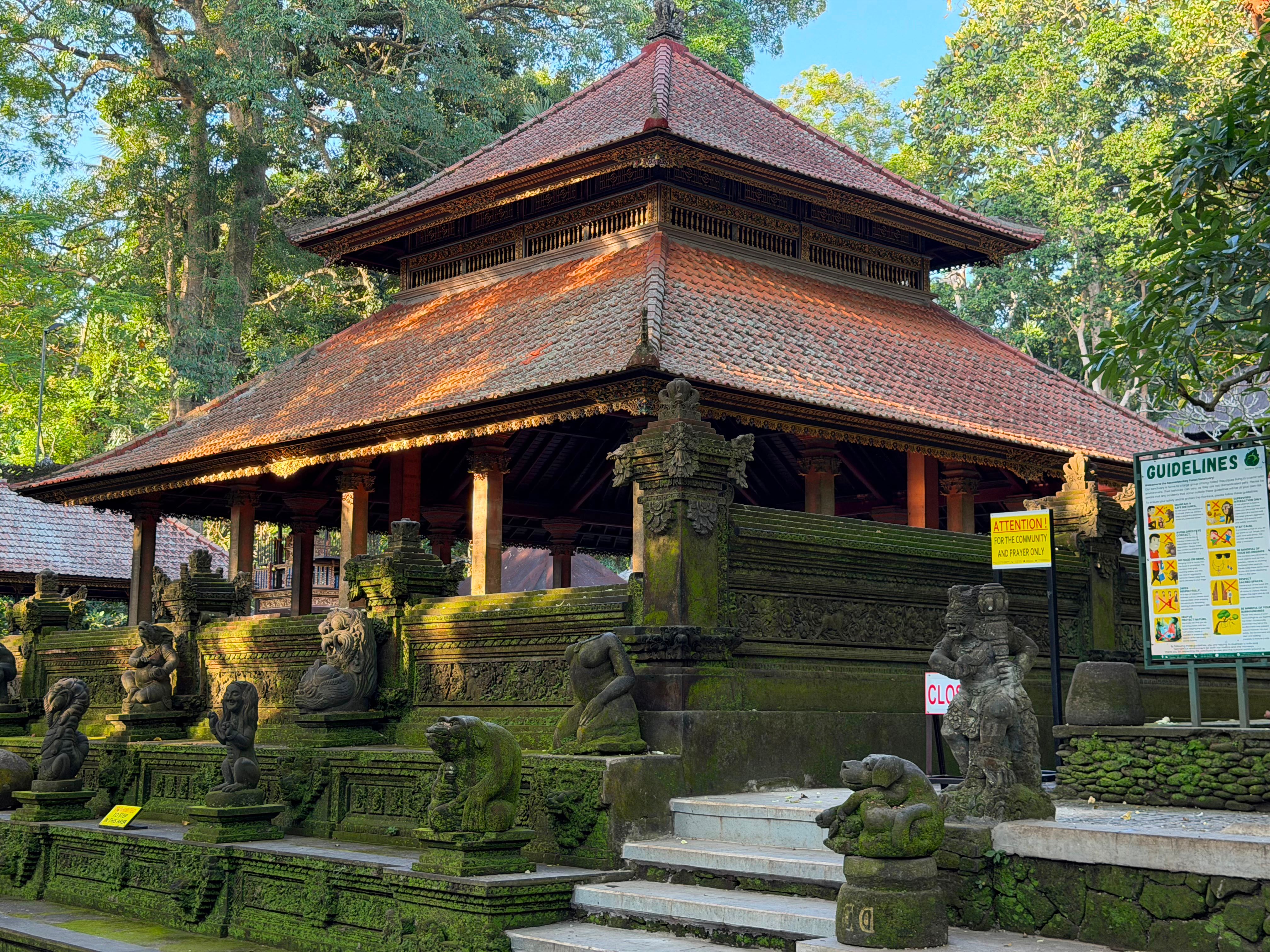 Balinese temple with intricate stone carvings and lush greenery in tropical landscape.