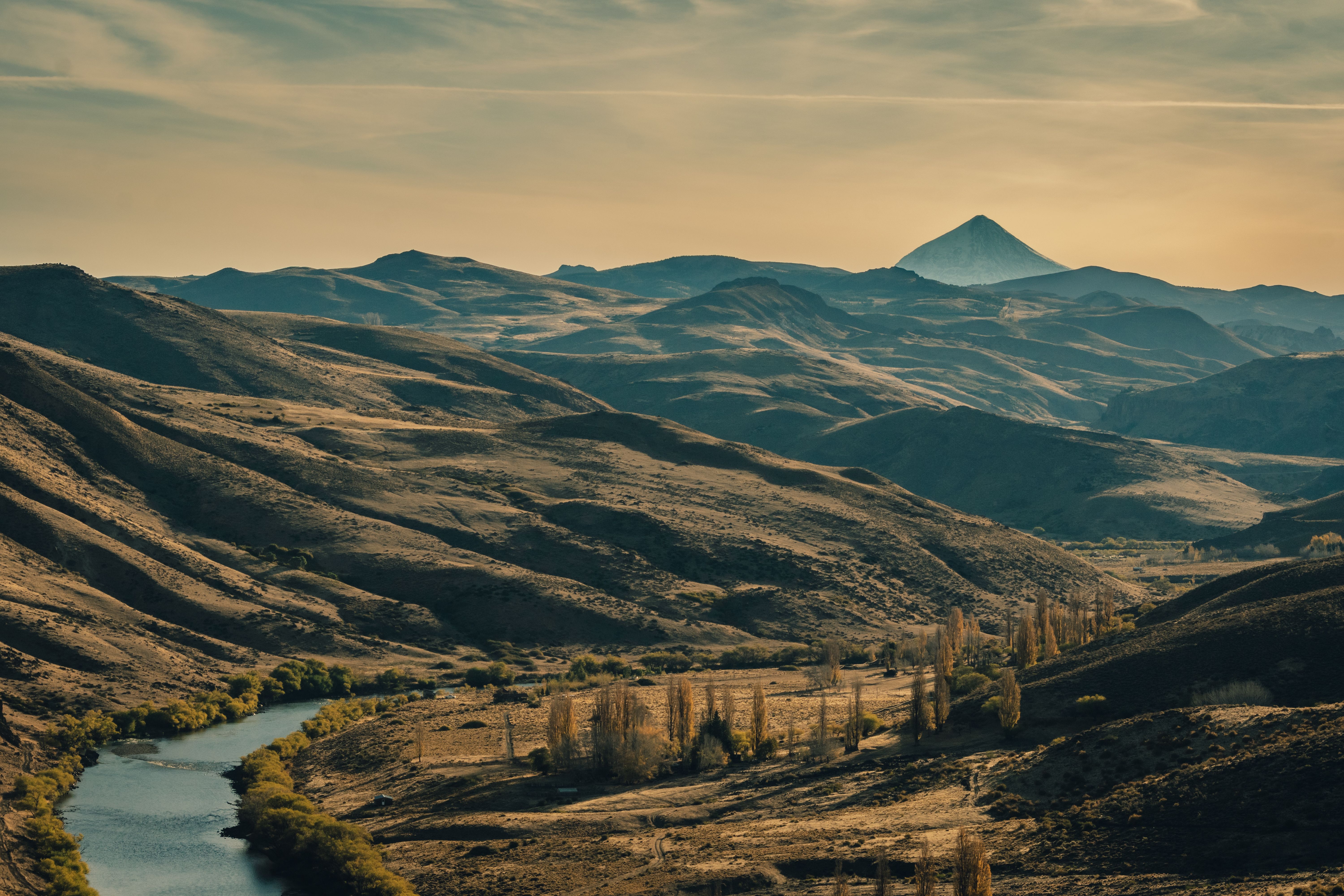 Fotomural Una vista impresionante de las ondulantes montañas y el río en Neuquén, Argentina, durante la puesta de sol.