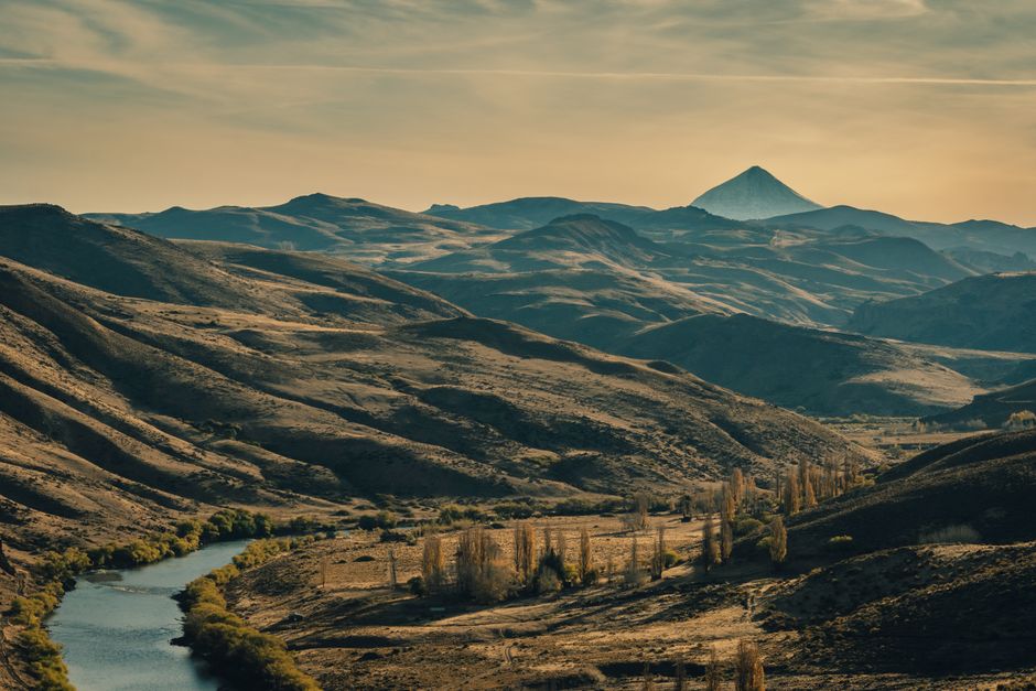 Fotomural Una vista impresionante de las ondulantes montañas y el río en Neuquén, Argentina, durante la puesta de sol.