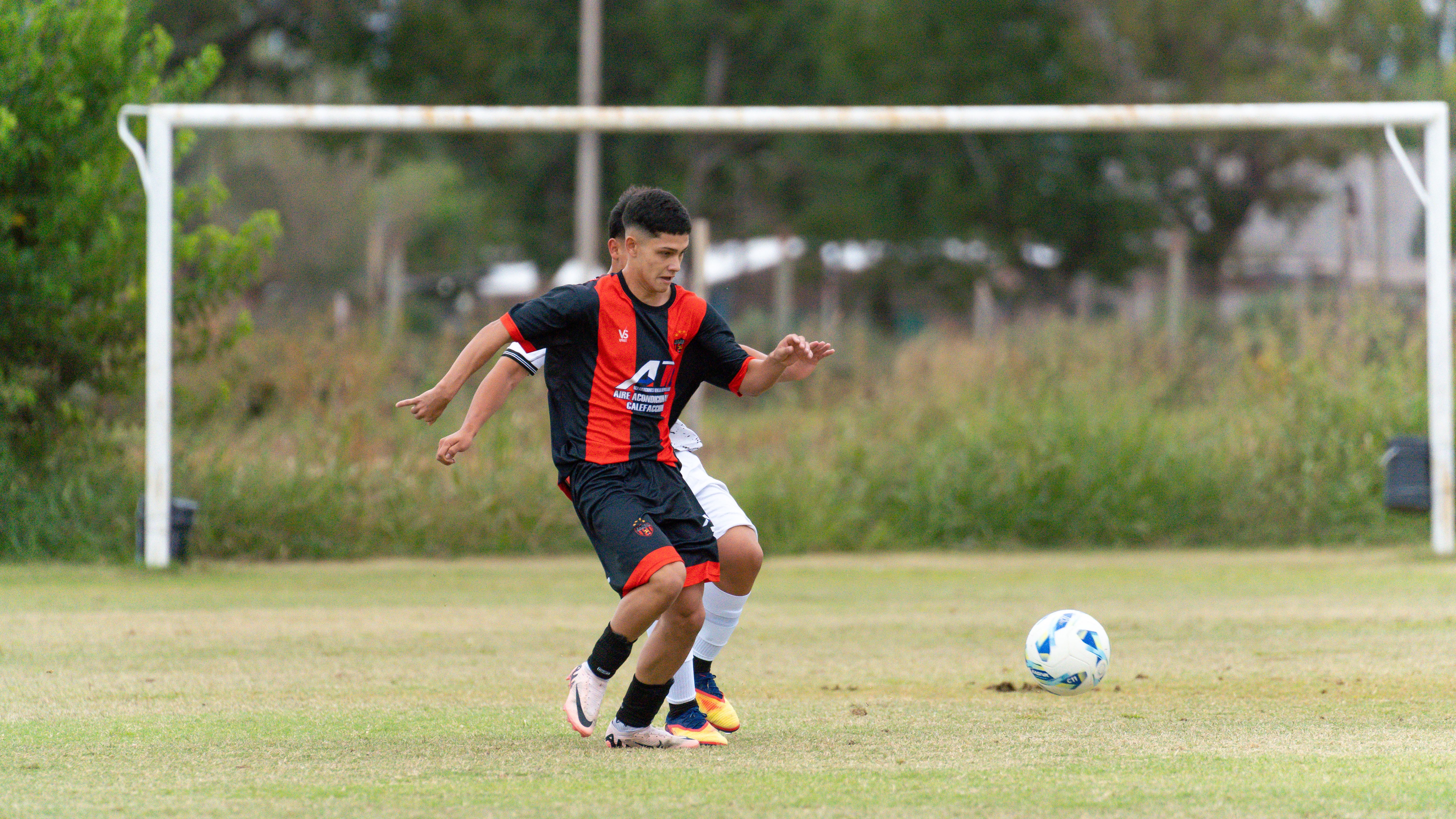 Two young athletes compete in a soccer match on a grass field.