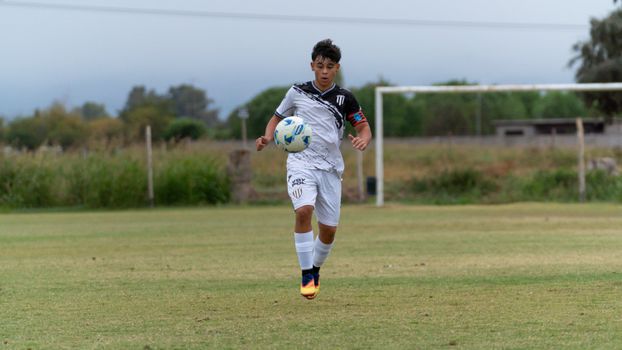 Teenager playing soccer on a grassy outdoor field, showcasing sportsmanship and athleticism.