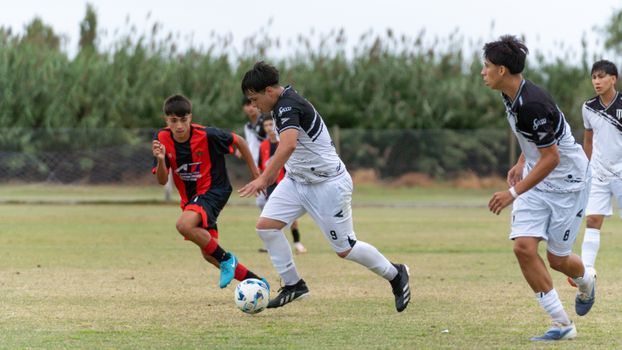 Dynamic action shot of teenagers playing soccer outdoors on a grassy field.