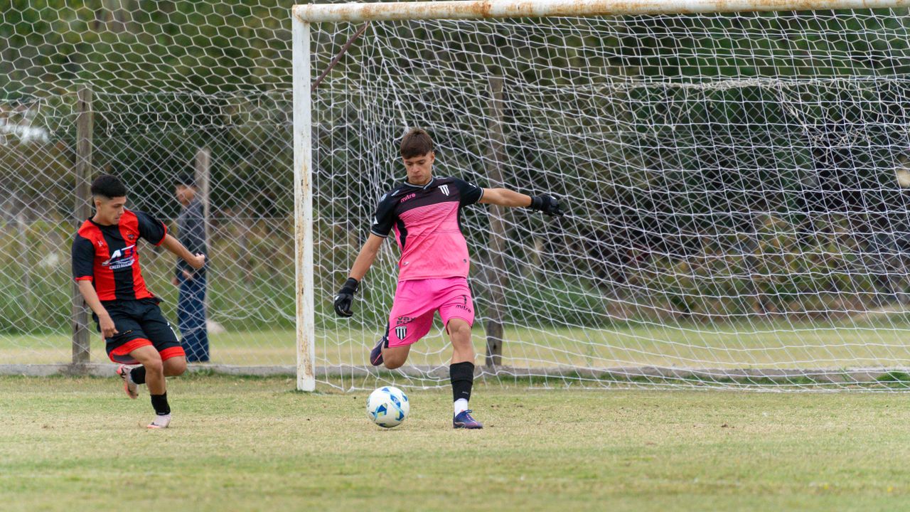 two teenage soccer players in action defending and scoring on an outdo