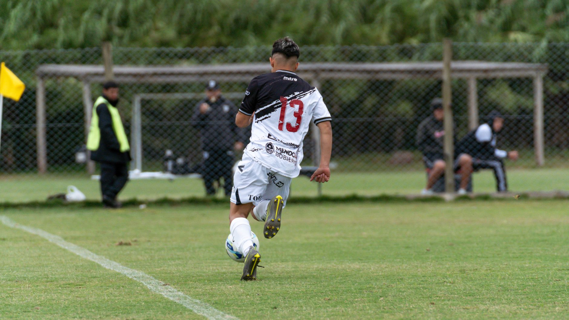 footballer completing resisted sprint training beside cones and a stopwatch on an outdoor practice field
