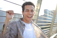 一个快乐的年轻人在阳光灿烂的日子里，站在桥上，拥抱积极和快乐的肖像