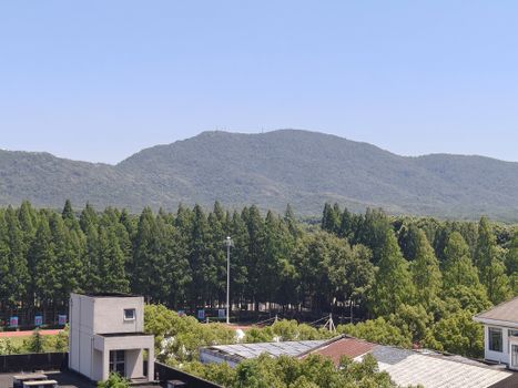 Panoramic view of a mountain landscape with lush greenery and rooftops under a clear blue sky.