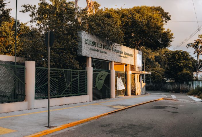 Sunlit entrance of Parque das Dunas in Natal, RN, showcasing greenery and architectural design.
