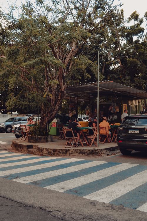 Free Street cafe scene in Natal, Brazil with people enjoying the outdoor dining experience under trees. Stock Photo