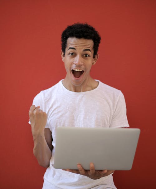 Free Man in White Crew Neck T-shirt Holding Laptop Stock Photo