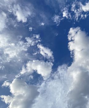 Clear blue sky filled with fluffy white clouds on a sunny day.