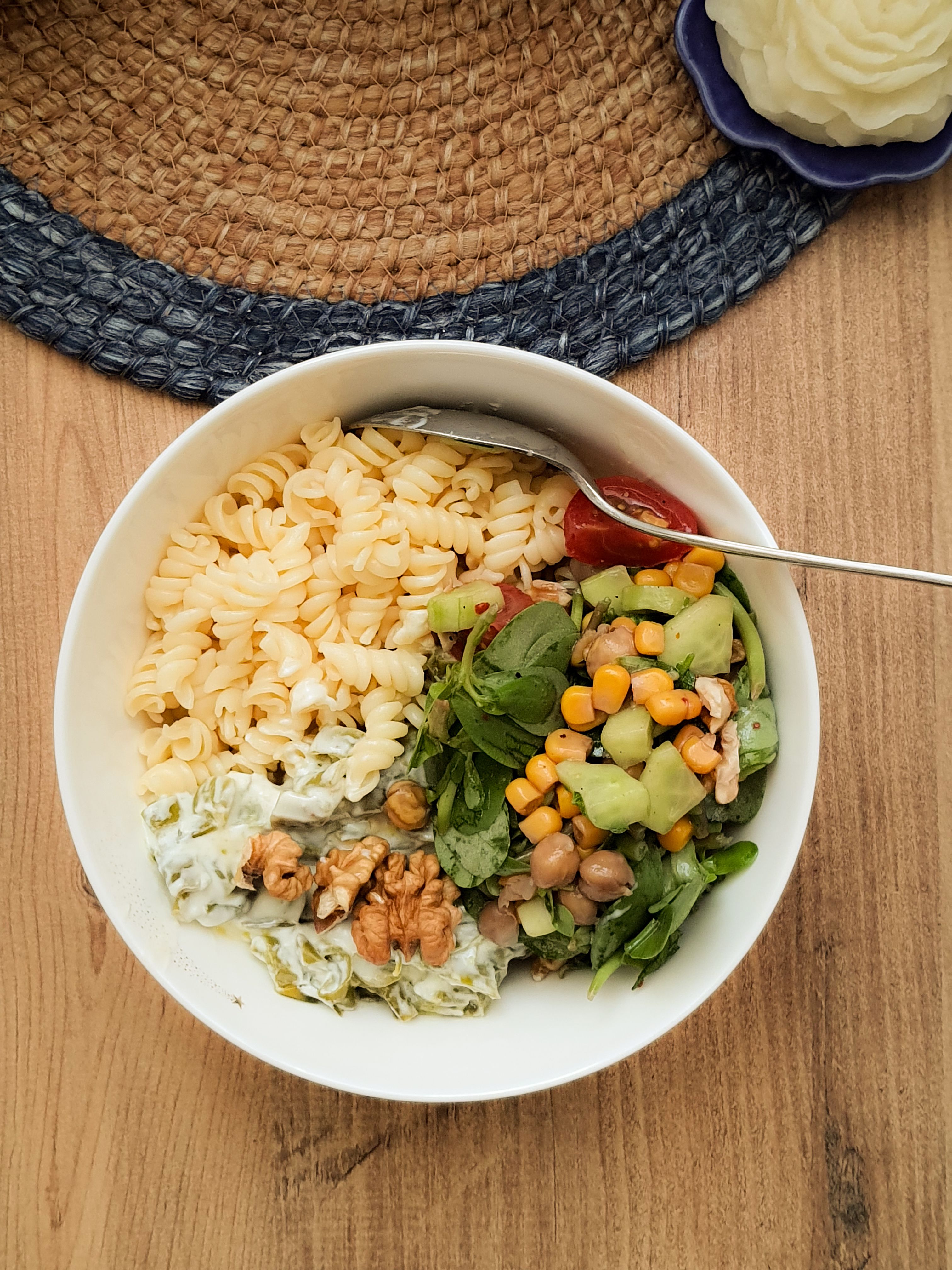 A delicious vegetarian bowl featuring pasta, salad, and walnuts. Perfect for a healthy meal.