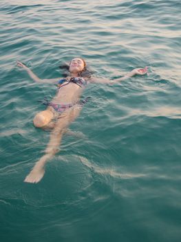A young woman floats effortlessly in clear ocean water, enjoying a peaceful day.