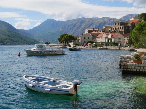 Free Charming coastal town with boats, mountains in the background, and clear blue waters, ideal for travel exploration. Stock Photo
