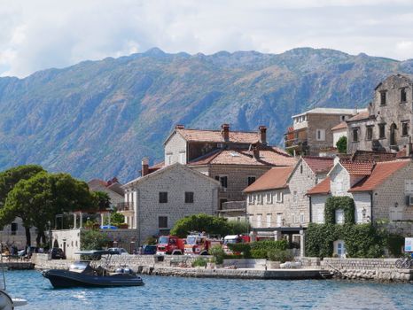 Charming stone buildings by the water in a Montenegrin coastal town with mountain backdrop.